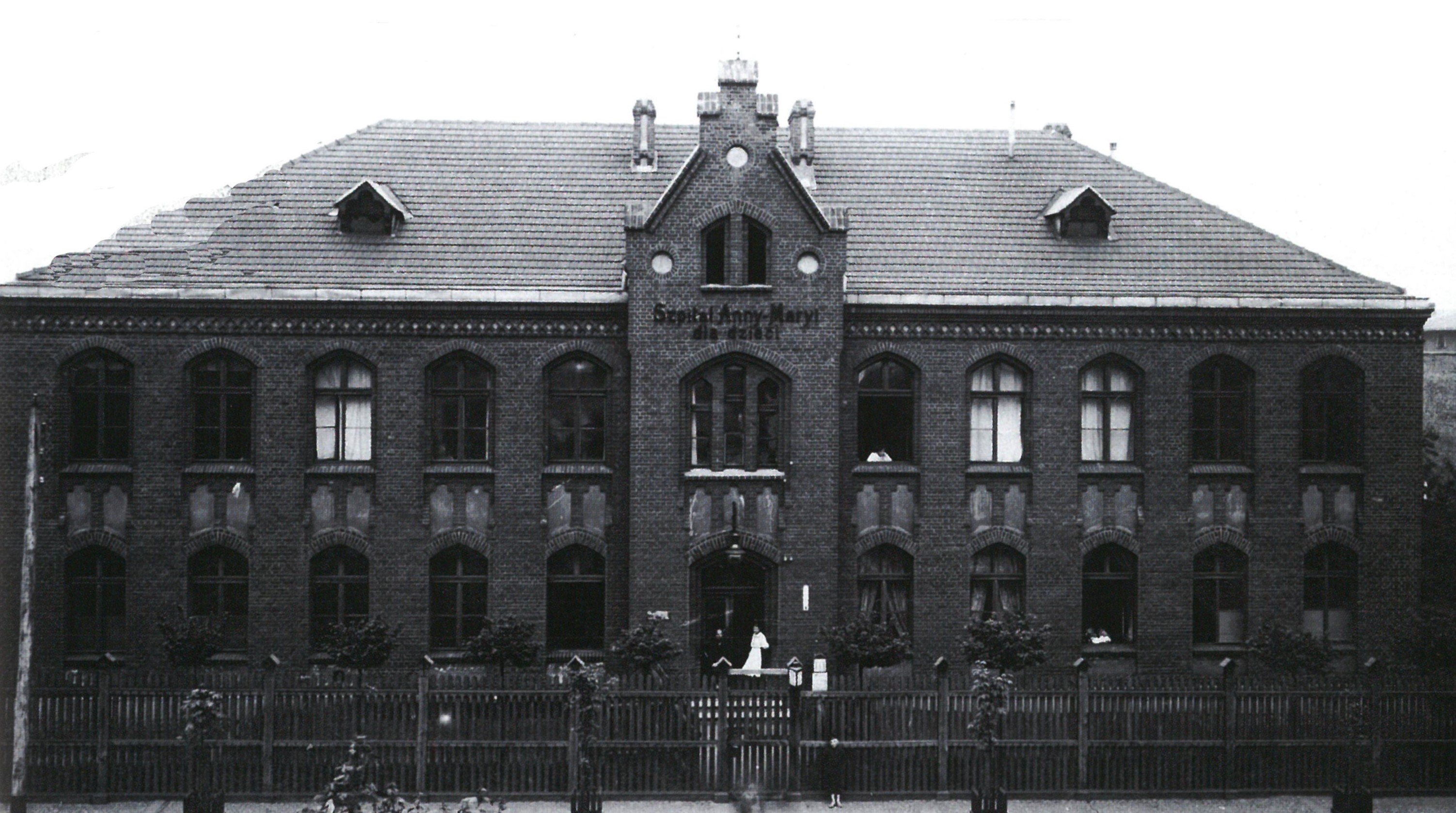 czarno-białe zdjęcie przedstawia piętrowy budynek ze spadzistym dachem